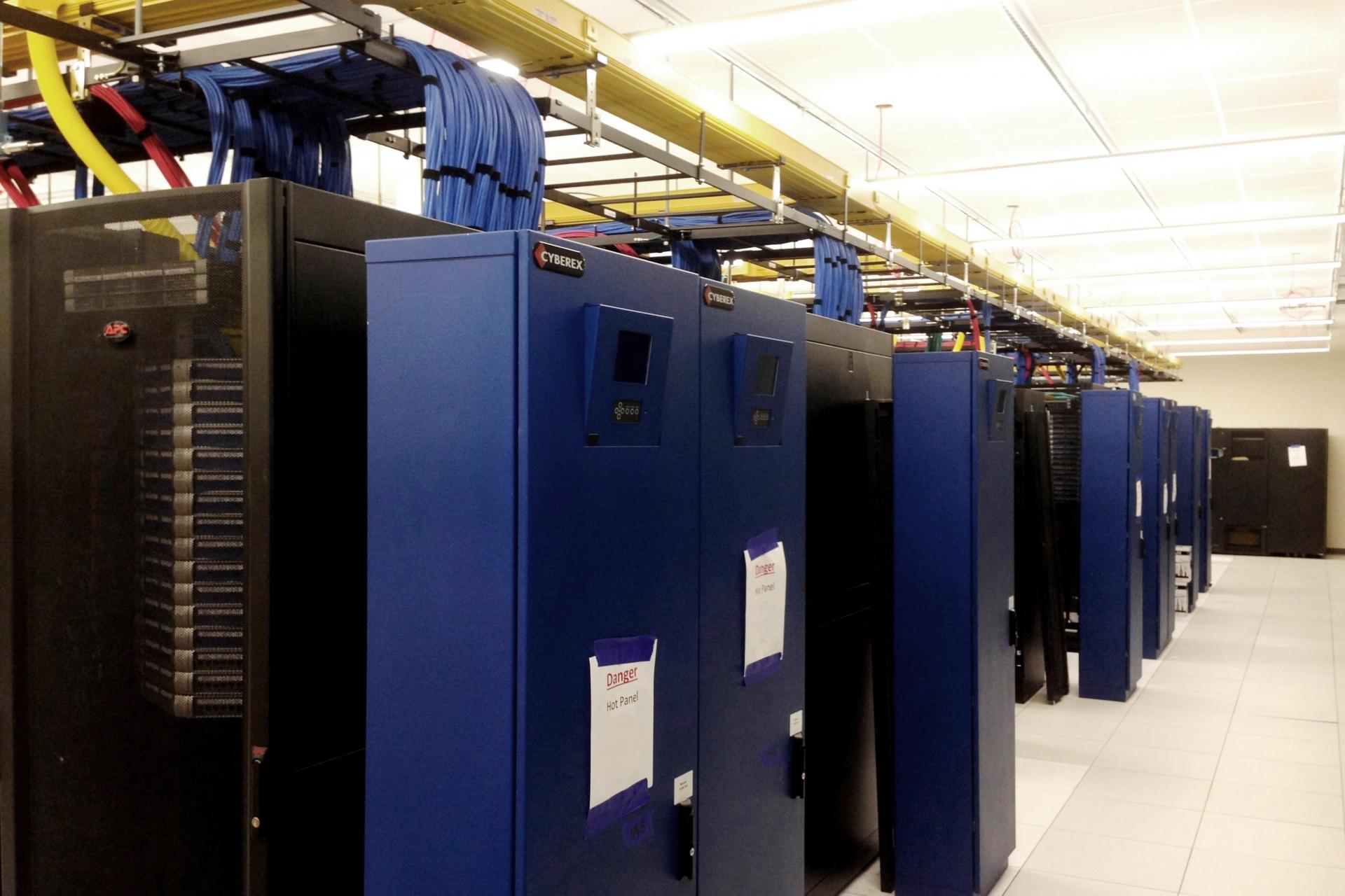 End of row remote power panels are color coded to identify the source power. Fiber and copper connectivity is distributed on overhead ladder rack and cable tray that are diversely routed to provide redundant connectivity.